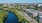 The Charley Apartments | Aerial view of a city with a river beside a busy road, bordered by green trees and modern buildings like The Charley Apartments in Allston, MA, all under a clear blue sky. | Boston Waterfront Apartments 