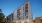 The Charley Apartments | Modern six-story apartment building, The Charley Apartments in Allston MA, features balconies, illuminated windows, and street lamps at dusk. Several parked cars line the quiet street, with neighboring buildings visible in the bac
